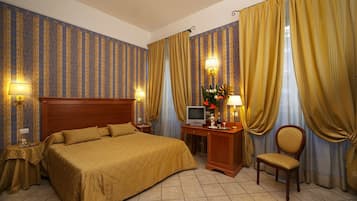 Una habitación de hotel con una cama grande, un escritorio con televisión y una silla.