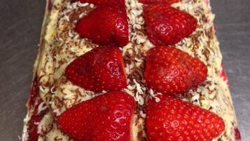 Un postre rectangular con fresas y virutas de chocolate sobre un plato blanco.