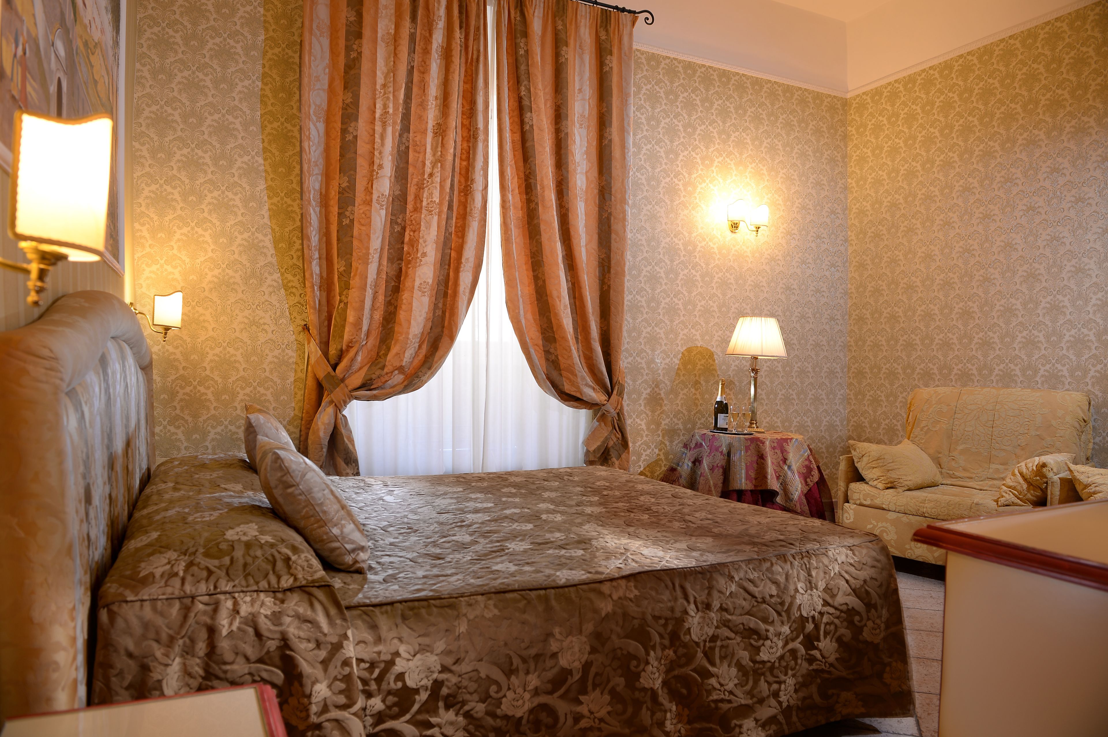 A hotel room with a large bed, a sofa, and two lamps.