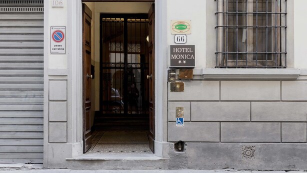 The entrance to Hotel Monica, featuring a wrought iron gate, a sign indicating the hotel name, and a disabled parking sign. - Hotel Monica (Florence)