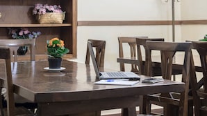 A wooden table with a laptop, a notebook, and a pen. There are chairs around the table. - Hotel Monica (Florence)