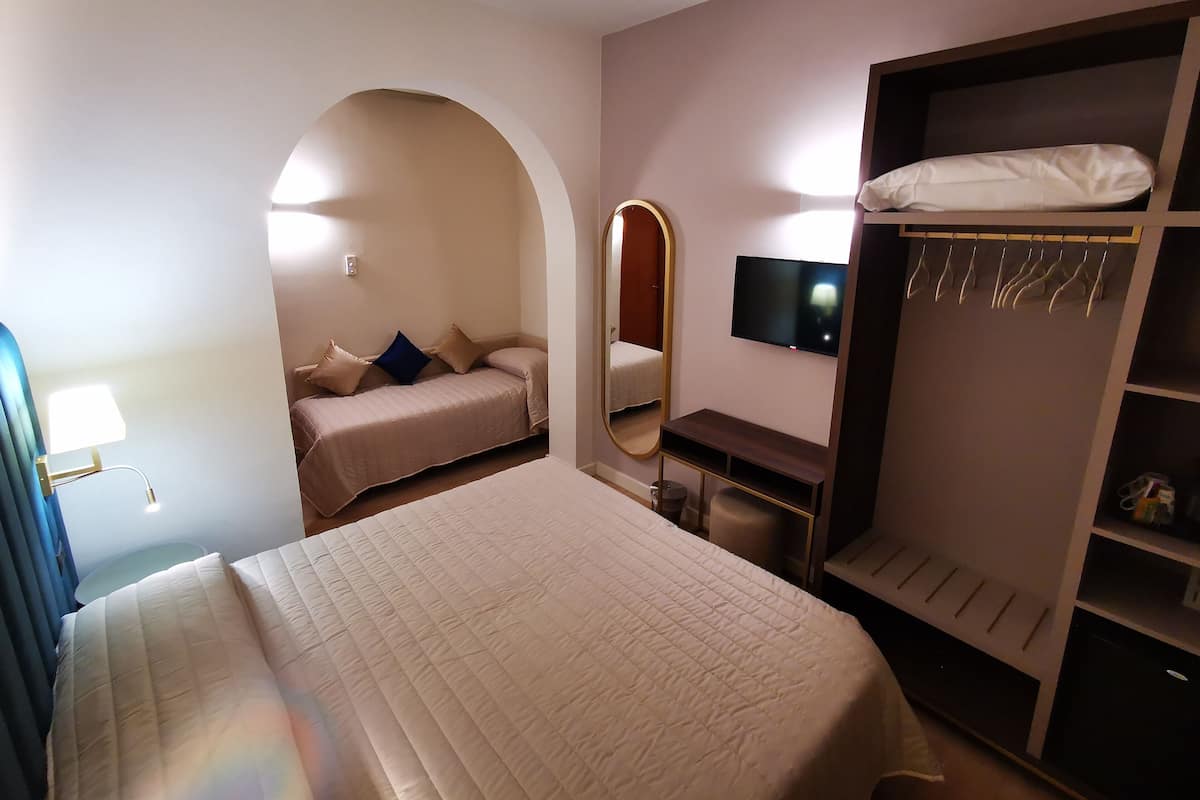 A bedroom with a bed, a desk, a TV, and a wardrobe.