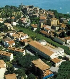 Une vue aérienne d’une ville côtière où les bâtiments sont très rapprochés les uns des autres, avec une église imposante et une vue dégagée sur la mer.