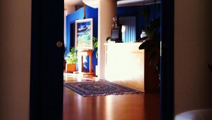 Ein hell erleuchtetes Wohnzimmer mit blauer Wand, einem Holzbüro und einem großen Gemälde.