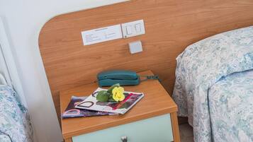 Ein Schlafzimmer mit einem hölzernen Kopfteil, einem Nachttisch mit Lampe, Telefon und Zeitschrift.