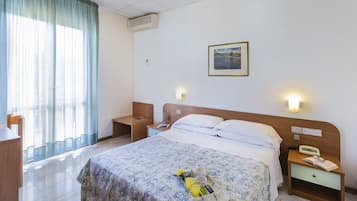 Een hotelkamer met een bed, nachtkastjes, een bureau en een raam met gordijnen.
