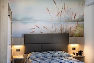 Un dormitorio con cama, mesita de noche, estante en la pared y un mural de un lago.