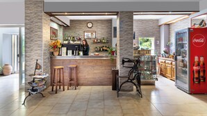 A bar area with stools, a refrigerator, and shelves with bottles.
