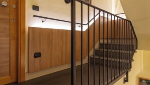 Una escalera con barandilla de metal negro, una puerta de madera y un letrero sobre la puerta.