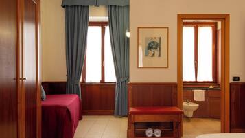 A room with two beds, a wooden bench, a sink, and a framed picture on the wall.