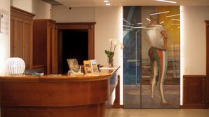 Una recepción con encimera de madera, un jarrón con flores y un cuadro de una persona en la pared.