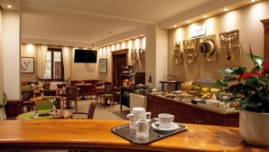 Comedor de hotel con diversas opciones de asientos, un bufé con distintos tipos de comida y un televisor colgado en la pared.