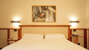 Habitación de hotel con una cama grande, dos mesitas de noche, un cuadro en la pared y lámparas de pared.
