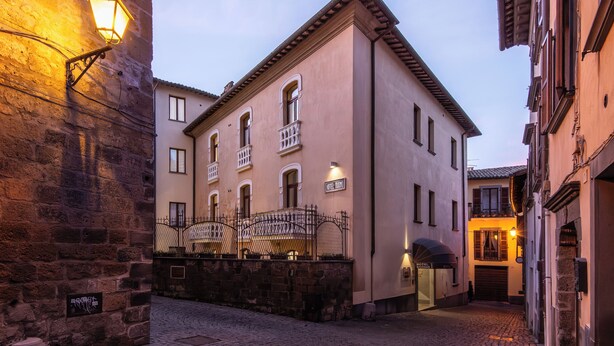Un edificio histórico con fachada de piedra, entrada porticada y un cartel que indica 'Hotel D'Or'.