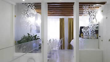 Ein modernes Interieur mit Glastrennwand, einer Uhr und einem Essbereich mit transparenten Stühlen und einem Tisch.
