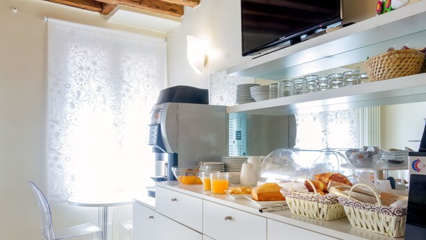 A modern kitchen with a coffee machine, breakfast items, and baskets on the counter. - Hotel Adriatico (Venice)