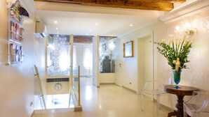 A hallway with a wooden ceiling, a clock, a staircase, and a vase with flowers. - Hotel Adriatico (Venice)