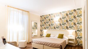 A hotel room with a large bed, a bedside table, a chair, and a desk. - Hotel Corso (Orvieto)