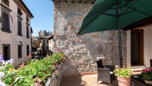 A stone building with a tiled patio, outdoor seating, and potted plants. - Hotel Corso (Orvieto)