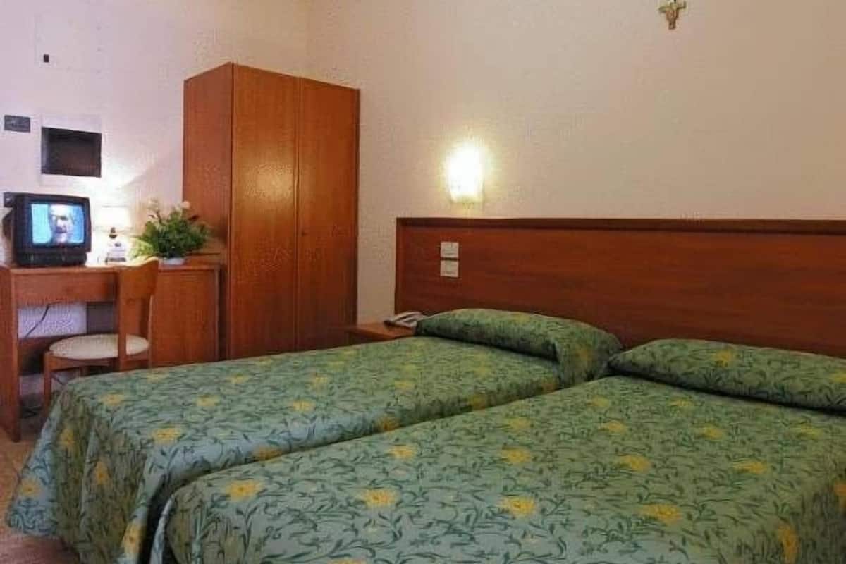 A hotel room with two beds, a desk with a television, and a wardrobe.
