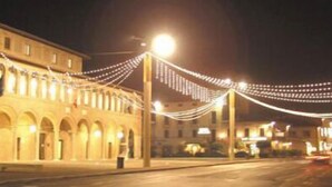 A building with arched windows and a street with string lights. - Porziuncola (Assisi)
