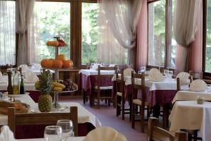Un restaurant où les tables sont dressées pour le service, avec une présentation de fruits et des bouteilles disposées sur les tables.