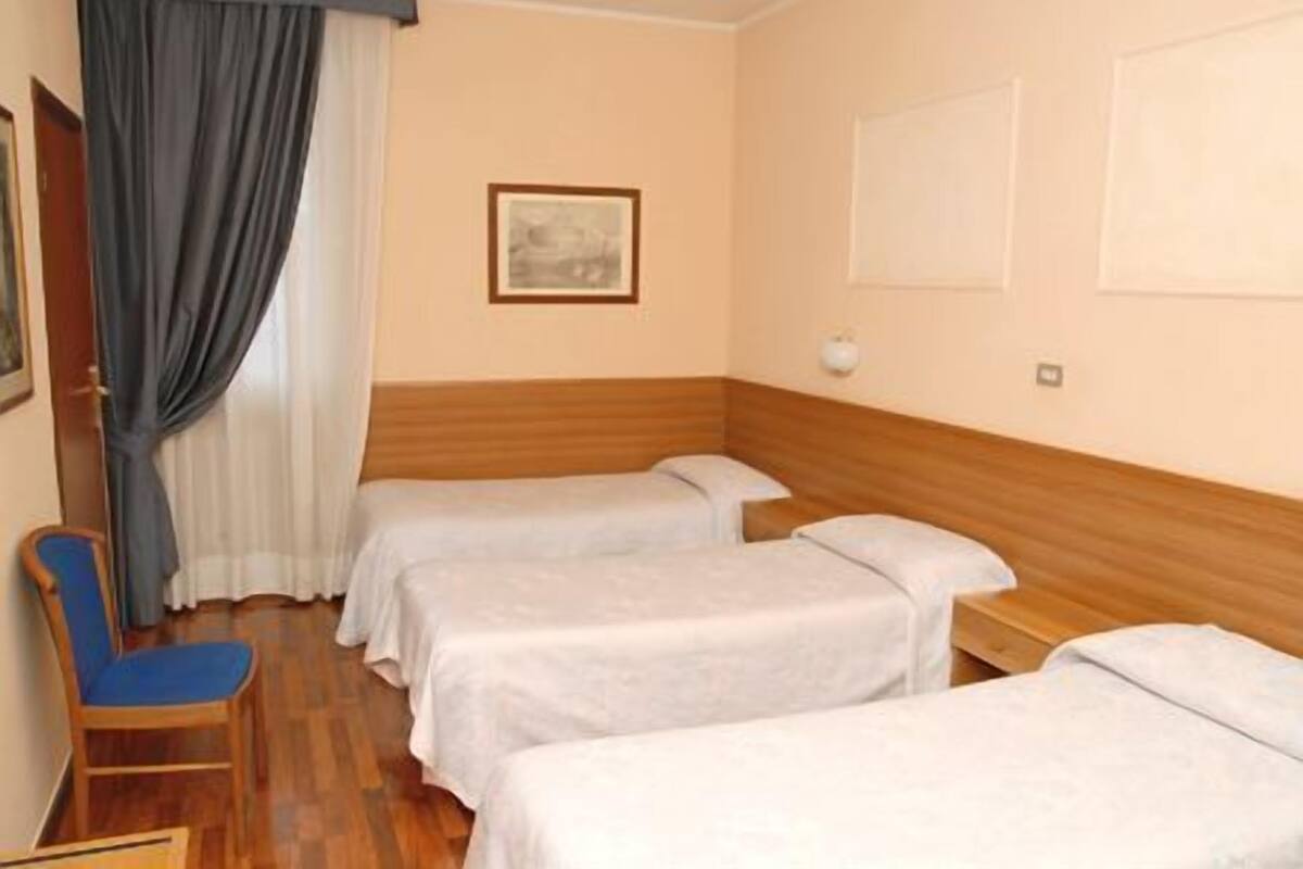 Ein Hotelzimmer mit zwei Einzelbetten, einem Holzkopfstück, einem Sessel und einem Bild an der Wand.