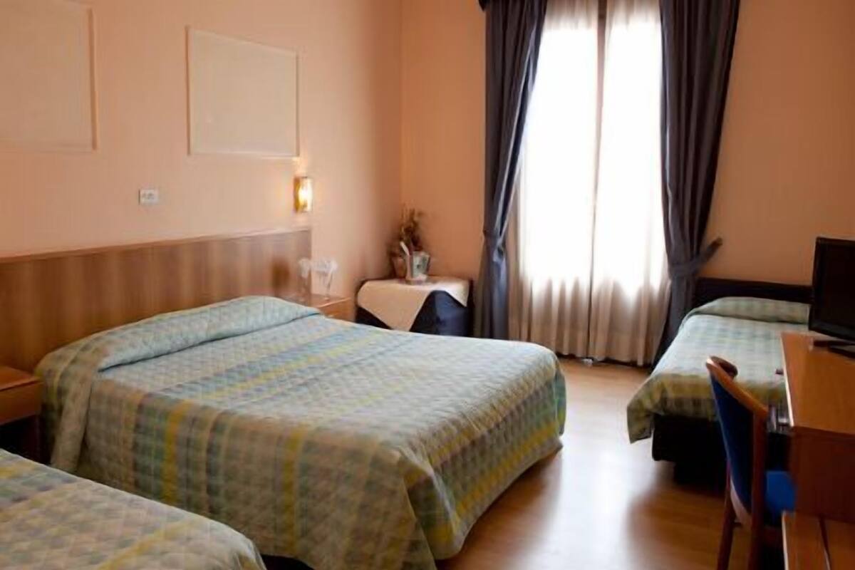 Ein Hotelzimmer mit zwei Betten, einem Schreibtisch, einem Stuhl und einem Fernseher.