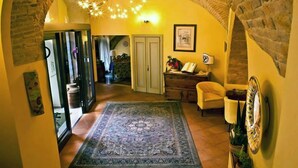 A hallway with a patterned rug, a wooden cabinet, and a chair. - Hotel San Giacomo (Assisi)