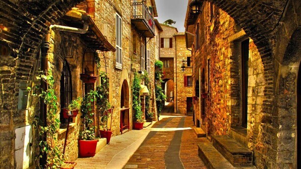 A narrow stone alleyway with arched openings, potted plants, and traditional stone buildings. - Hotel San Giacomo (Assisi)