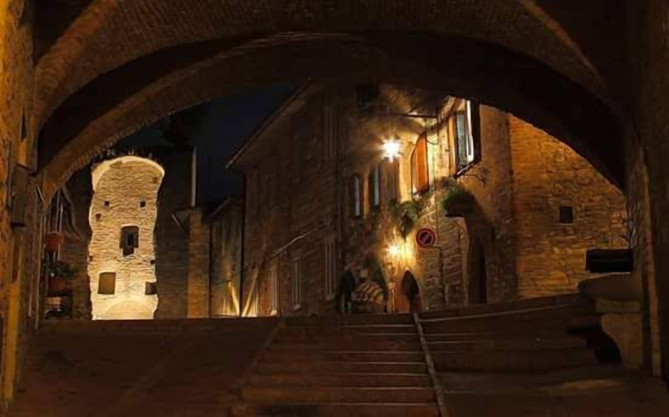 Un arco in pietra che conduce a un edificio con una scala e una torre.