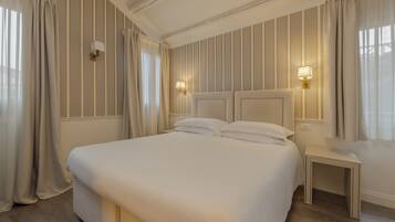 Una camera d'albergo ordinata con un letto grande, due comodini e lampade a parete.