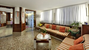 A modern living room with a striped sofa, a coffee table, and a potted plant. - Hotel Caprera (Venice)