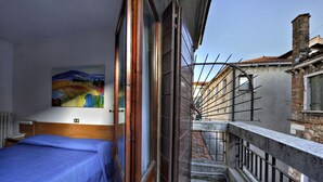 A narrow corridor with a wooden door, a metal railing, and a staircase leading to a balcony. - Hotel Caprera (Venice)