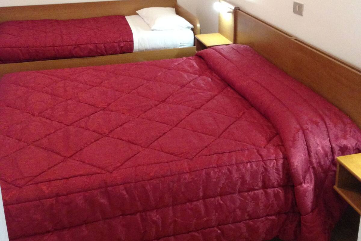 A room with a large bed, a bedside table, and a wall-mounted lamp.