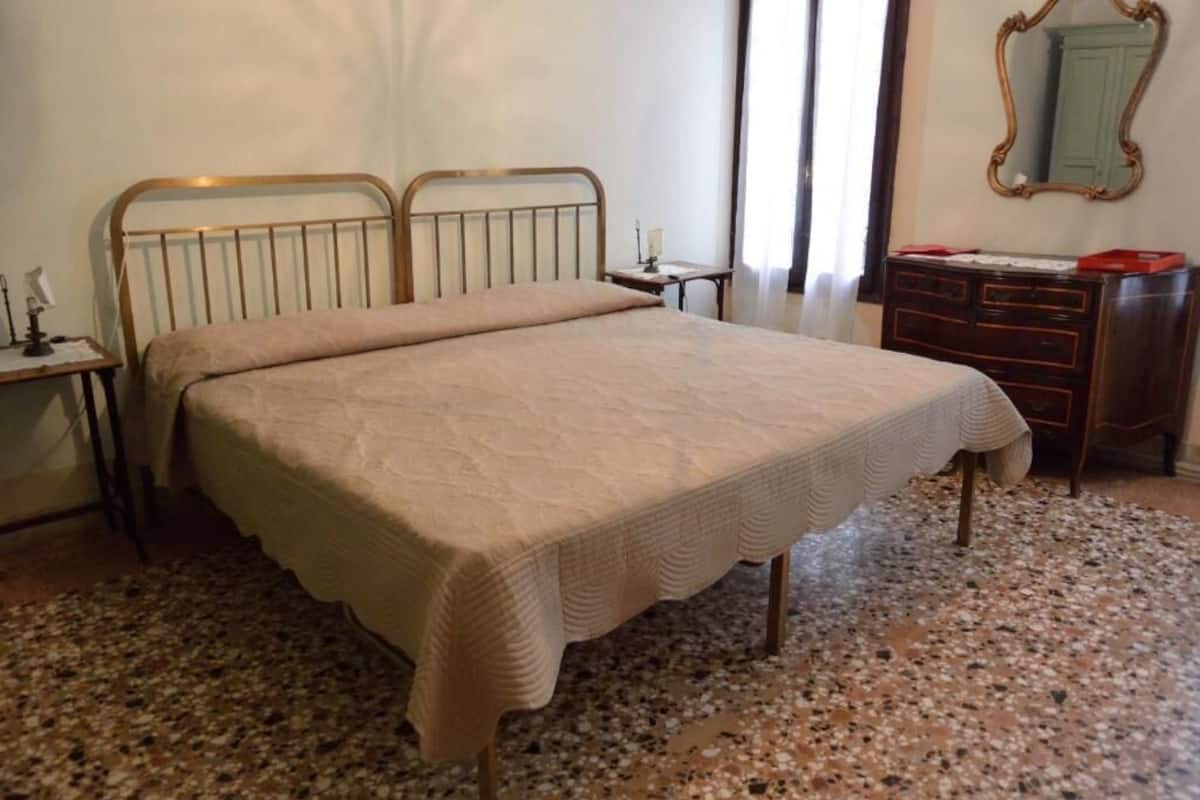 Una camera da letto con un letto, una cassettiera, un comodino e uno specchio.