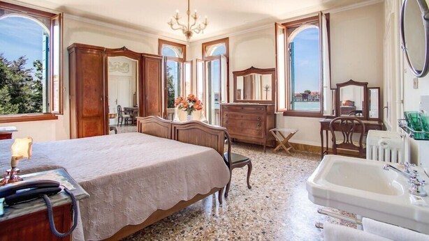 Un dormitorio con una cama grande, un aparador, una tocador con espejo y una bañera.