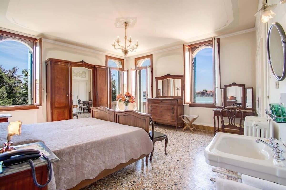 Una camera da letto con un letto grande, una cassettiera, una toeletta con specchio e una vasca da bagno.