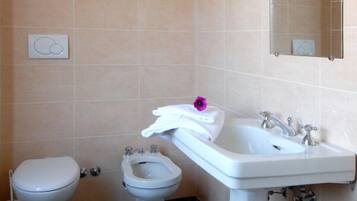Une salle de bain équipée de toilettes, d’un bidet et d’un lavabo.