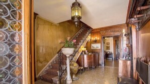 Una imponente escalera con barandilla de hierro forjado, un farol decorativo y un jarrón con flores.