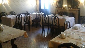 Un comedor con varias mesas y sillas, una chimenea y apliques de pared.