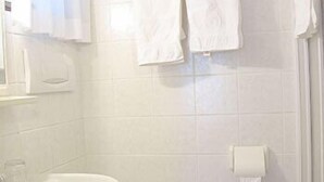Kylpyhuone, jossa on valkoinen pesuallas, wc ja laatoitetut seinät.
