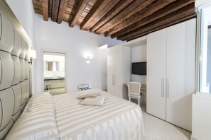 A bedroom with a large bed, a chair, a TV, and a wardrobe. - Hotel Campiello (Venice)