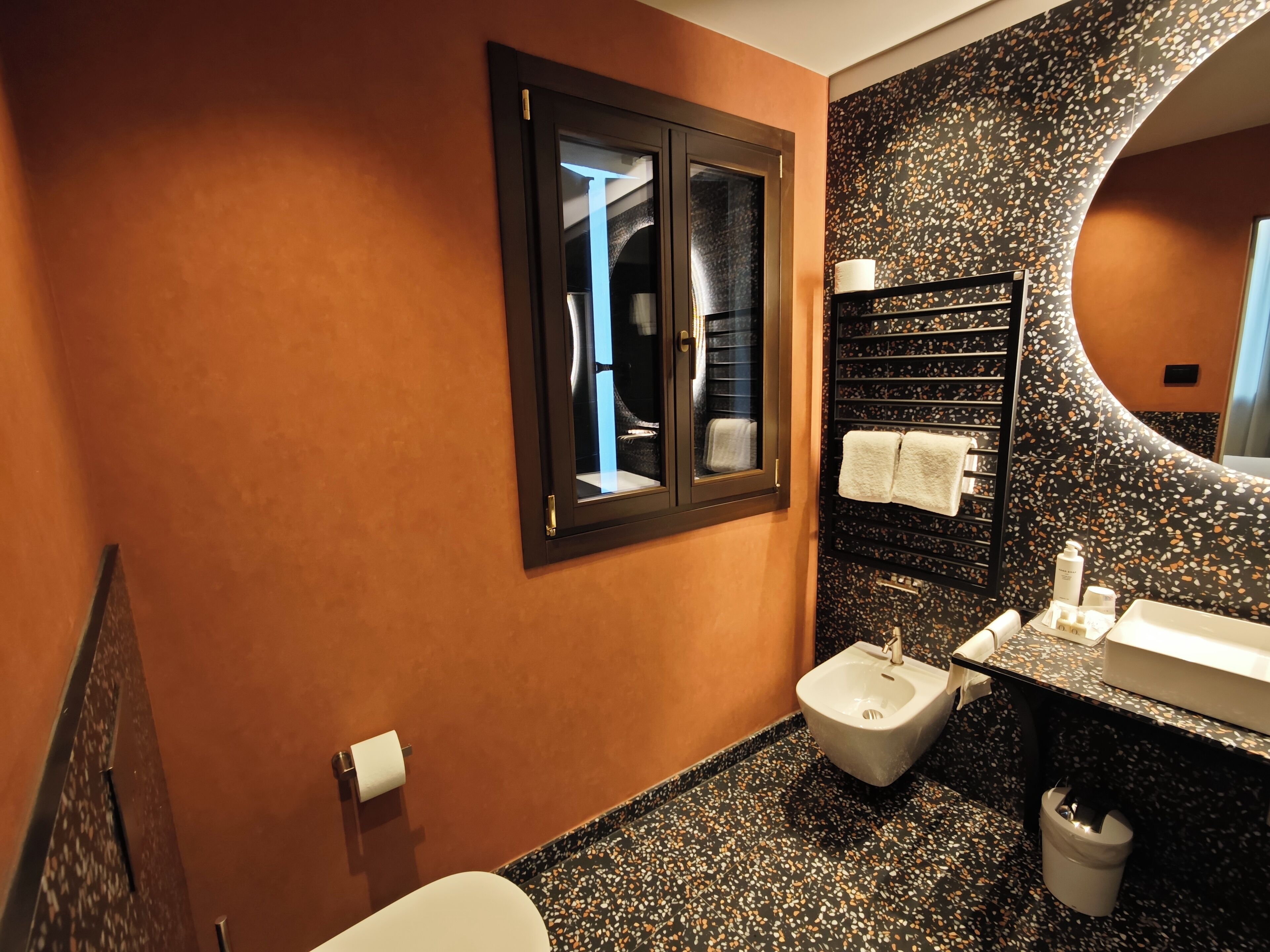 A modern bathroom with a bidet, a sink, and a mirror.