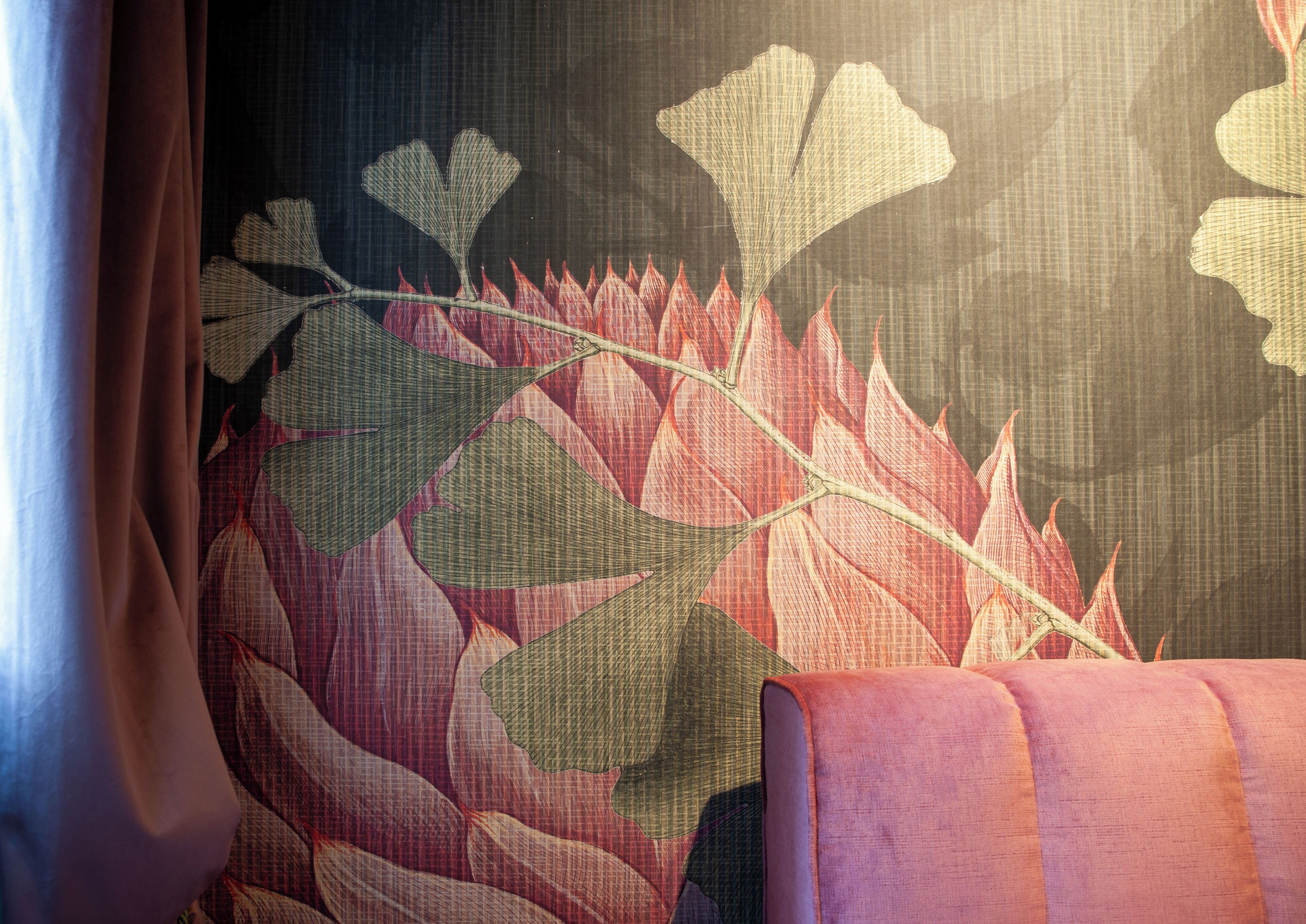 A room with a patterned wall, a window with curtains, and a sofa.