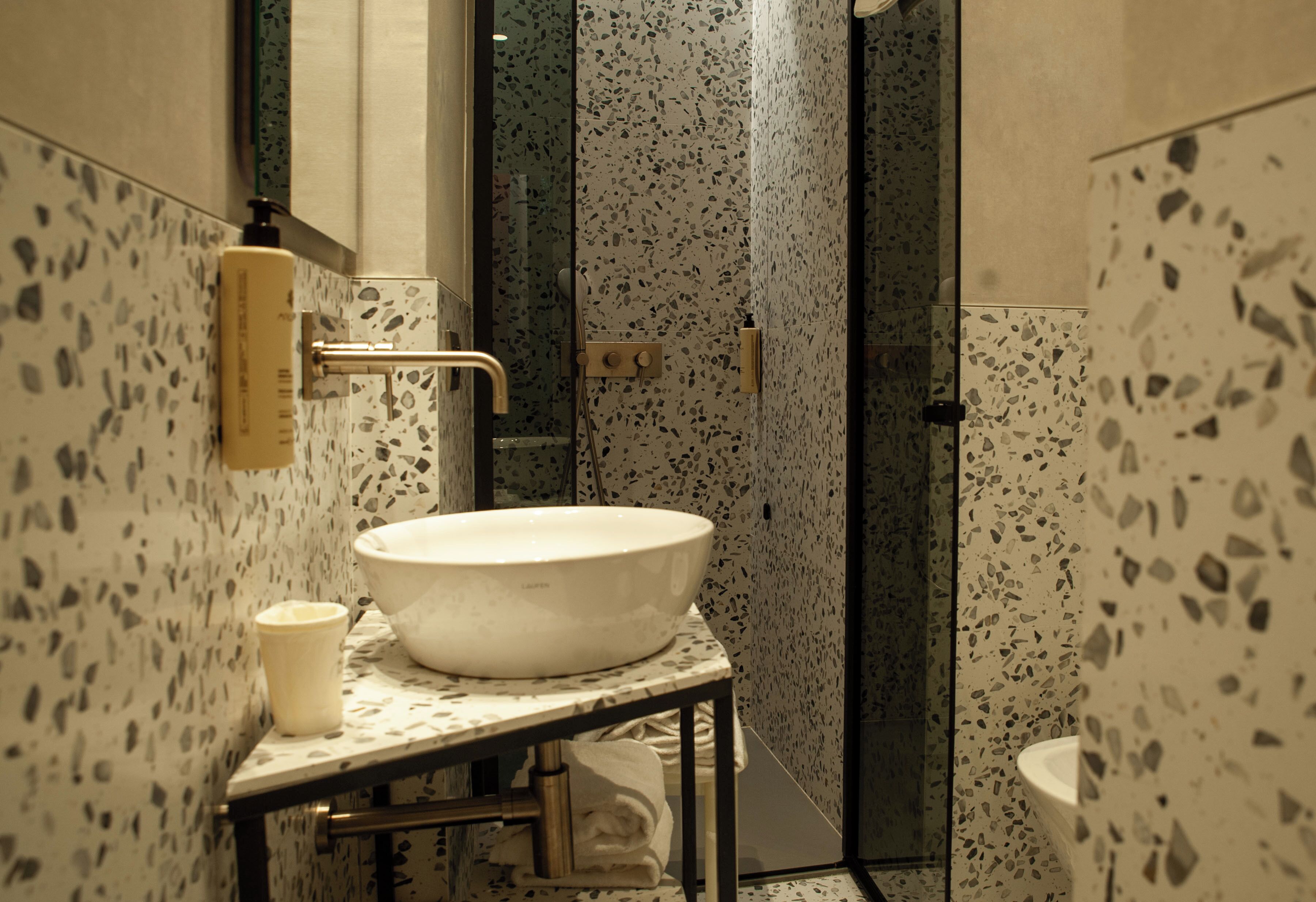 A bathroom with a freestanding sink, a towel rack, a glass shower enclosure, and a toilet.