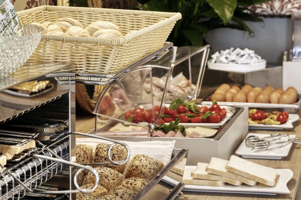 Un bufé con diversos alimentos, incluyendo pan, pasteles y frutas frescas.