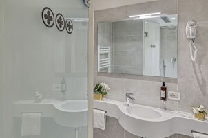Un bagno moderno con due lavabi, un grande specchio e un asciugacapelli fissato alla parete.