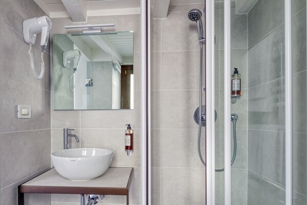 A modern bathroom with a large white sink, a hairdryer mounted on the wall, and a glass-enclosed shower area. - Hotel Al Nuovo Teson (Venice)