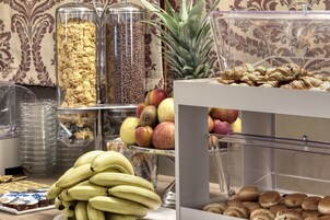 Un bufé con diferentes opciones de comida, incluyendo plátanos, manzanas y pasteles.